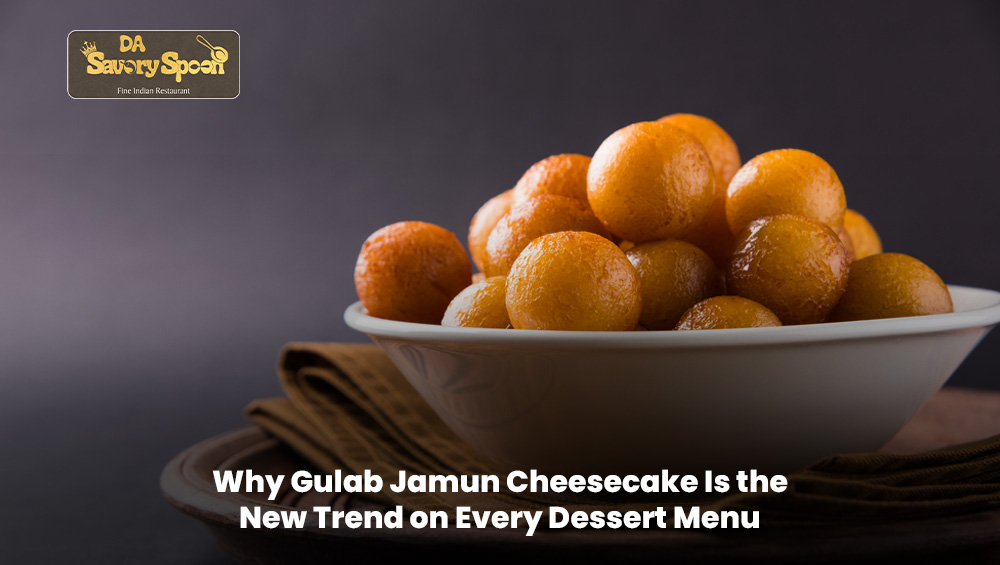 A slice of Gulab Jamun Cheesecake topped with syrup and garnished beautifully on a dessert plate.