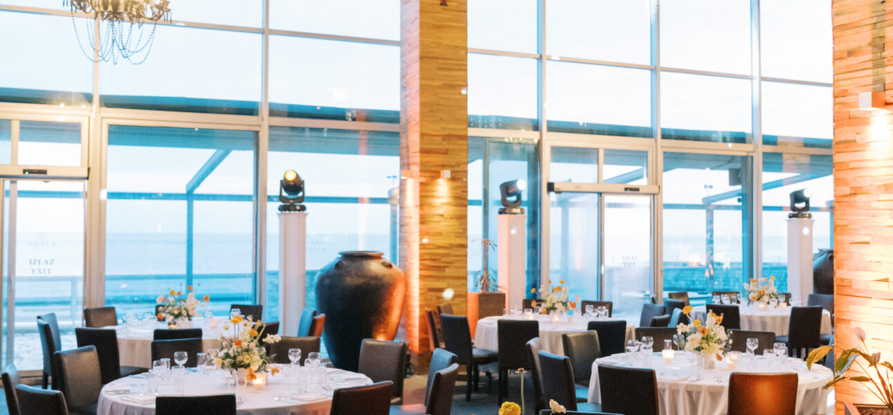 Round served festive tables in a restaurant with high windows and columns