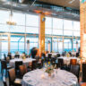 Round served festive tables in a restaurant with high windows and columns