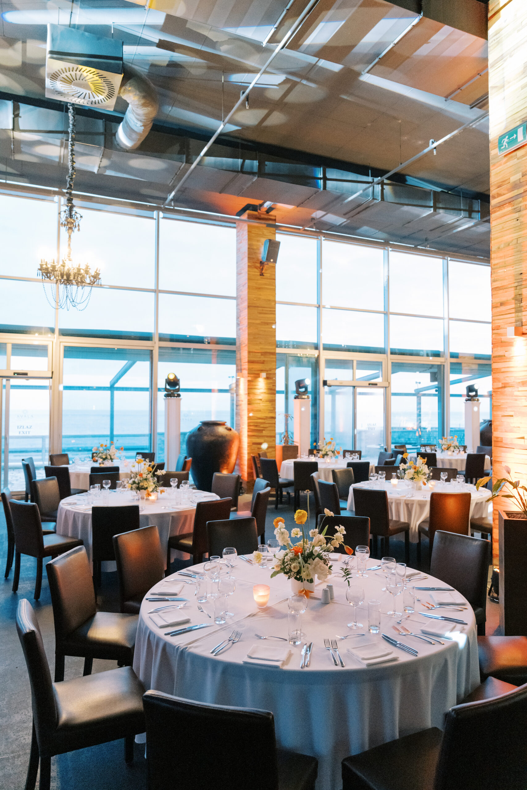 Round served festive tables in a restaurant with high windows and columns